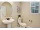 Clean half bathroom featuring a pedestal sink, toilet, mirror, and a window with a modern wall hanging at 7099 E 123Rd Pl, Thornton, CO 80602