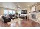 Bright and airy living room with hardwood floors, large windows, comfortable seating, and a stone fireplace at 7099 E 123Rd Pl, Thornton, CO 80602