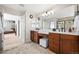 Dual sink vanity bathroom with wood cabinets and a large mirror and adjoined bedroom at 27290 E Nova Cir, Aurora, CO 80016