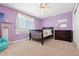 Bright bedroom with a large window, a dark wood crib, dresser, light purple walls, and neutral carpet at 27290 E Nova Cir, Aurora, CO 80016