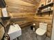 Rustic bathroom features a modern sink and toilet with wood paneled walls and floating shelves at 352 Apache Rd, Evergreen, CO 80439