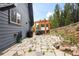 Stone patio with hot tub, grill, and access to the home's back entrance, surrounded by nature at 352 Apache Rd, Evergreen, CO 80439