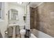 Compact bathroom featuring a pedestal sink, toilet, and shower-tub combination with patterned curtain at 1532 N High St # 1, Denver, CO 80218