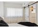 Bright bedroom with a large window covered by white curtains and a sliding barn door at 1532 N High St # 1, Denver, CO 80218