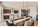 Dining area with long table and chairs, modern lighting fixture, and a view to the modern kitchen at 14440 Hop Clover Trl, Parker, CO 80134