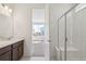 Bright bathroom view featuring a glass shower stall with bench, double sink vanity, and an open doorway at 9314 Biscay St, Commerce City, CO 80022