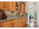 Elegant butler's pantry with wooden cabinets, granite countertops, tile backsplash, and views to breakfast nook at 4651 Sonado Pl, Parker, CO 80134