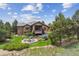 Expansive backyard with a fire pit, patio, lush lawn, mature trees, and manicured garden beds at 4651 Sonado Pl, Parker, CO 80134