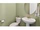 Powder room featuring a pedestal sink, round mirror, and light green walls at 17692 Olive St, Broomfield, CO 80023