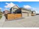 Three-car garage with modern doors, complemented by a stylish wooden fence and concrete driveway at 17692 Olive St, Broomfield, CO 80023