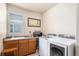 Laundry room with modern appliances, including a front-load washer and dryer, with counter space and storage cabinets at 14058 Elizabeth St, Thornton, CO 80602