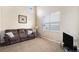 Bright living room with a comfortable sofa, large window, and a TV on a glass stand creating a cozy atmosphere at 14058 Elizabeth St, Thornton, CO 80602