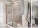 Tiled shower with glass doors, built-in bench, and shower head, next to a door opening to a living room at 14058 Elizabeth St, Thornton, CO 80602