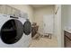 Spacious laundry room featuring a modern washer and dryer, cabinetry and tile flooring at 15088 Verbena St, Thornton, CO 80602