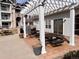 Outdoor patio area with a pergola, brick flooring, picnic tables, grill and manicured landscaping at 15700 E Jamison Dr # 3-202, Englewood, CO 80112