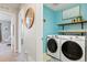 Laundry room with blue walls, modern washer and dryer, and wood shelving at 8427 E 35Th Ave, Denver, CO 80238