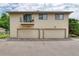 A two-story exterior featuring two garage doors, a balcony, and assigned parking at 3351 S Field St # 191, Lakewood, CO 80227