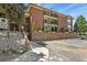 Exterior side view of condo showing balconies and entrance, with mature trees and lush landscaping at 13950 E Oxford Pl # A-104, Aurora, CO 80014