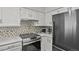 Modern kitchen with stainless steel oven, smooth cooktop, new appliances, white cabinets, and stylish backsplash at 13950 E Oxford Pl # A-104, Aurora, CO 80014