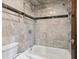 Bathroom features a bathtub and shower with elegant marble tile surround and convenient storage at 8822 E Florida Ave # G07, Denver, CO 80247