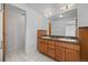 Bathroom featuring a double vanity with wood cabinets, granite countertops, and tiled floors at 7700 E 29Th Ave # 102, Denver, CO 80238
