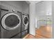 Laundry area featuring modern washer and dryer units, adjacent to an open doorway and light wood floors at 7700 E 29Th Ave # 102, Denver, CO 80238