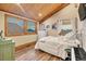 Inviting bedroom features a sloped wood ceiling, ample natural light, wood floors, and a charming vintage dresser at 11524 Spruce Mountain Rd, Larkspur, CO 80118