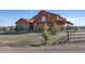 Wood home with a barn and covered patio surrounded by a split rail fence and greenery at 11524 Spruce Mountain Rd, Larkspur, CO 80118
