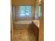 Bathroom featuring large soaking tub with tile surround and double sinks at 213 Mesa St, Brighton, CO 80601