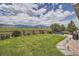 Sprawling backyard featuring a stone fire pit, green lawn, and picturesque mountain views at 9527 Iron Mountain Way, Arvada, CO 80007