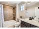 Well-lit bathroom with a shower-tub combo, neutral tile, and a modern vanity with dark wood cabinets at 9527 Iron Mountain Way, Arvada, CO 80007