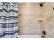 Modern bathroom with beige tile surround, shower head, and striped shower curtain at 9527 Iron Mountain Way, Arvada, CO 80007
