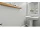 Simple powder room with pedestal sink, mirror, and wall shelves at 6139 Raleigh Cir, Castle Rock, CO 80104