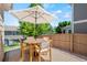 A charming patio is staged with wooden furniture and a cream colored umbrella perfect for outdoor relaxation and entertainment at 6139 Raleigh Cir, Castle Rock, CO 80104