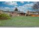 Lush backyard showing the back of house, with patio, green lawn, and mature trees at 4391 W Tufts Ave, Denver, CO 80236