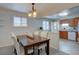 Dining room with a wood table set for four, open to kitchen and bright window at 4391 W Tufts Ave, Denver, CO 80236