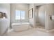 Bright bathroom featuring tub, walk-in shower with seat, and window at 2937 Hidden Den Ct, Franktown, CO 80116