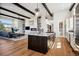 Open floor plan: kitchen island, hardwood floors, and living room with fireplace and beamed ceiling at 2937 Hidden Den Ct, Franktown, CO 80116
