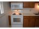 Traditional kitchen features a white range/oven, microwave and wood cabinets at 14702 E Security Way, Aurora, CO 80011