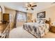 Cozy bedroom featuring a ceiling fan, window with blinds, and comfortable quilt bedding with an antique wood cabinet at 10776 Hillsboro Cir, Parker, CO 80134
