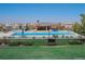 Community swimming pool featuring lounge chairs and umbrellas surrounded by lush greenery and houses at 10776 Hillsboro Cir, Parker, CO 80134