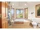 Charming bathroom with tiled tub, walk-in shower, and scenic views from multiple windows at 900 Sawmill Creek Rd, Evergreen, CO 80439