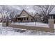 Charming two-story home featuring a well-maintained lawn and secure black metal fence with winter landscape at 1751 Clermont St, Denver, CO 80220