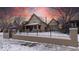 Charming two-story home featuring a well-maintained lawn and secure black metal fence with winter landscape at 1751 Clermont St, Denver, CO 80220