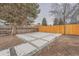 Spacious backyard featuring a concrete patio area, surrounded by gravel and a wooden fence at 4055 S Niagara Way, Denver, CO 80237