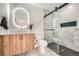 This primary bathroom has a wood cabinet, modern lighting and glass enclosed shower at 4055 S Niagara Way, Denver, CO 80237