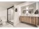 Sleek bathroom with dual sinks, floating wood vanity, and glass-enclosed shower at 4055 S Niagara Way, Denver, CO 80237