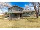 View of the backyard and home with green siding and a small covered back porch and yard at 8025 S Cody St, Littleton, CO 80128