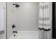 Modern bathroom featuring sleek tiles, a stylish shower head, and a bathtub with a black and white striped shower curtain at 8025 S Cody St, Littleton, CO 80128