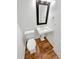 Modern powder room features hardwood floors, pedestal sink, framed mirror, and modern fixtures at 2180 Trailblazer Way, Castle Rock, CO 80109